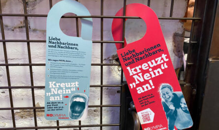 Flyer von NOlympia in Form von Türhängern. Links die Rückseite in hellblau mit den 3 Argumenten dagegen. Rechts die rote Vorderseite mit dem Text: Liebe Nachbarinnen und Nachbarn, bitte kreuzt „Nein“ an und dem QR-Code zu mehr Infos. Foto: Meret Büchner