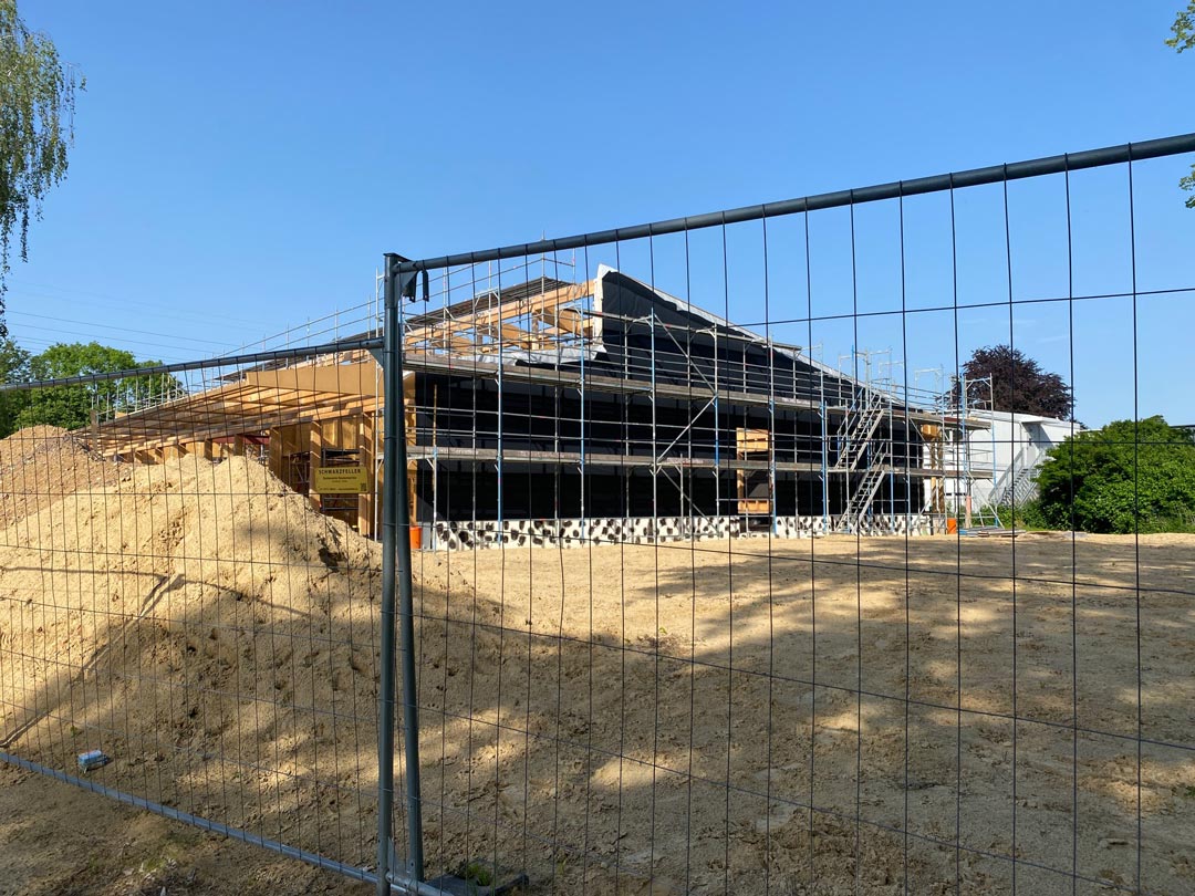 Die Holzkonstruktion von der Seite. Im Vordergrund eine große Sandfläche, die die Größe des Neubaus noch betont.