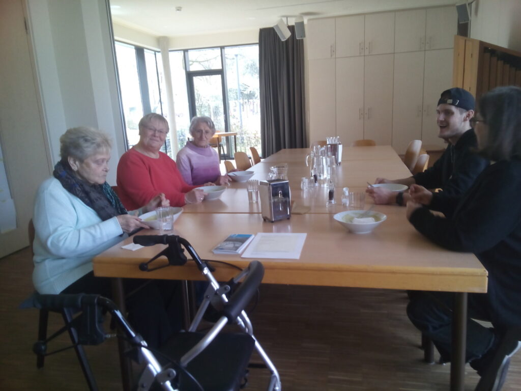 Mehrere Menschen am großen Tisch beim Essen in der Suppenküche