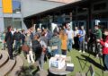 Viele Menschen vor der Schulmensa. Strahlender Sonnenschein.