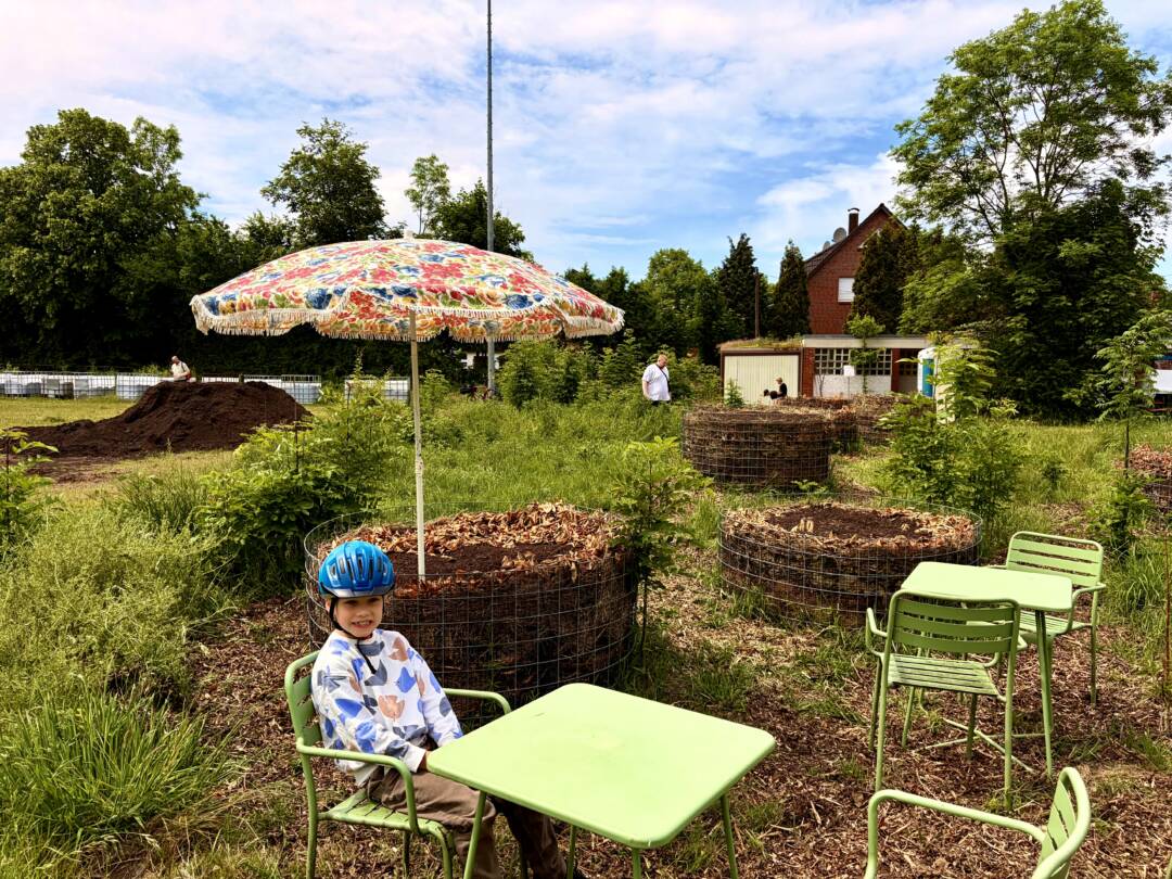 Kind sitzt im Garten des Lüttville Gelände