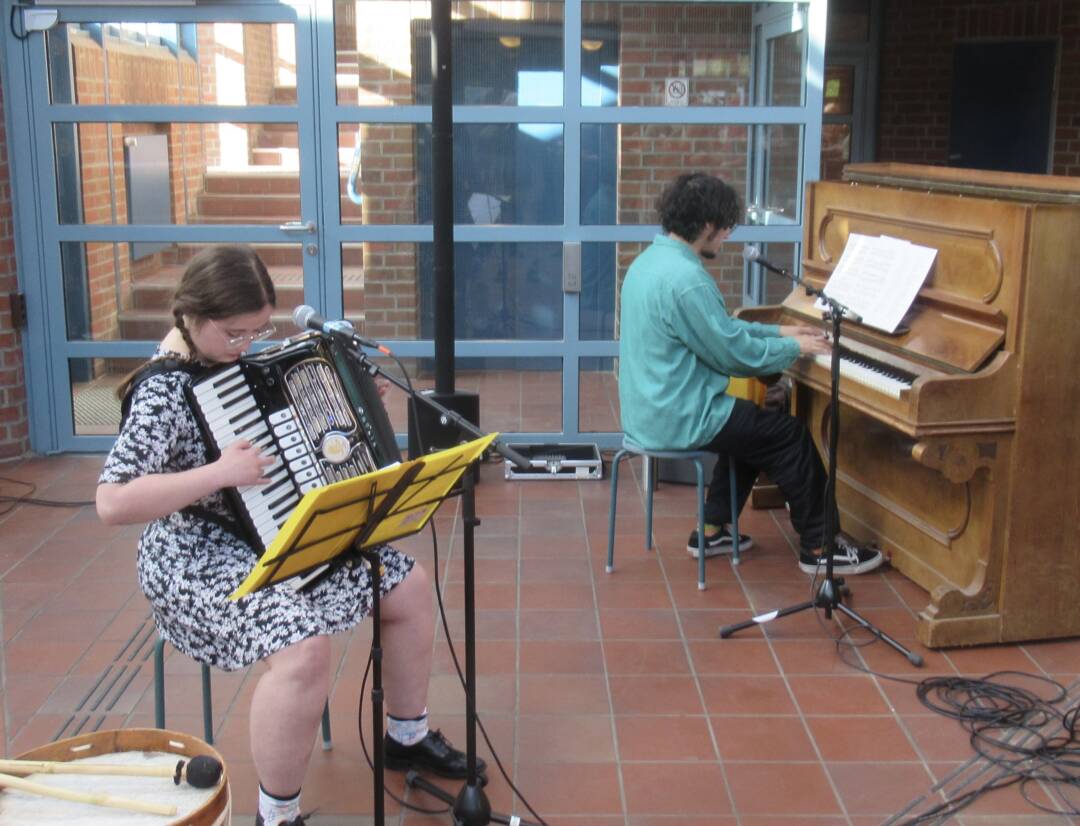 links eine Frau mit Akkordeon, eschts im Hintergrund ein Mann am Piano