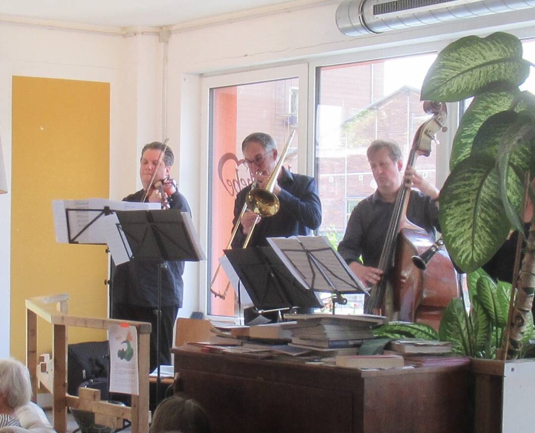Die drei Musiker (Geige, Posaune, Contrabass) im Kaffee Liebe vor dem großen Fenster. Foto: Hermann Kahle