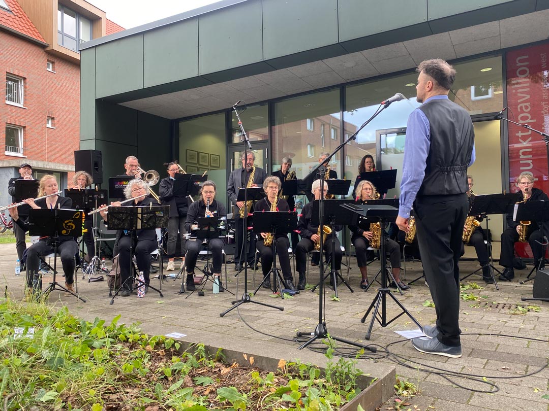 Die Band, hauptsächlich mit Blasinstrumenten, vor dem Treffpunkt Pavillon. Alle tragen schwarz.