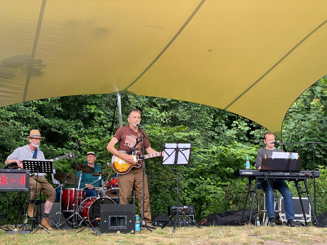 Die Band, 4 Männer, unter dem großen, gelben Sonnensegel.