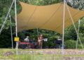 Die Band, 4 Männer, unter dem großen, gelben Sonnensegel.
