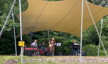 Die Band, 4 Männer, unter dem großen, gelben Sonnensegel.