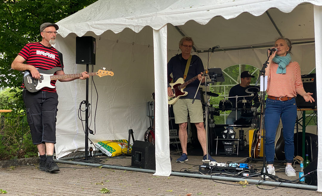 Die Band, 3 Männer und 2 Frauen, regensicher in einem weißen Pavillon. Die Keyboarderin ist nicht zu sehen.