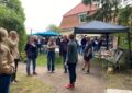 Männer und Frauen vor einem Haus mit rotem Ziegeldach.