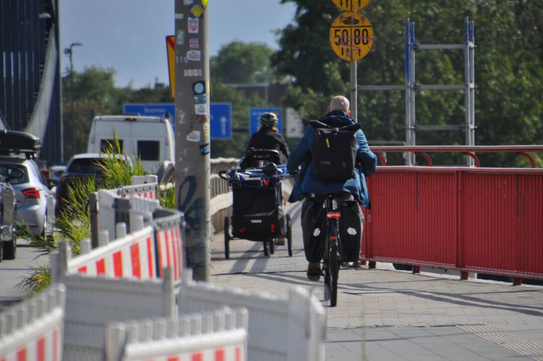 Blick auf den letzten Teil des Radweges auf den Neuen Elbbrücken stadteinwärts: Eine Radlerin mit Hänger fährt weiter vorn, es passt, aber viel Platz ist nicht. Dahinter ein Radler auf einem normalen Zweirad.