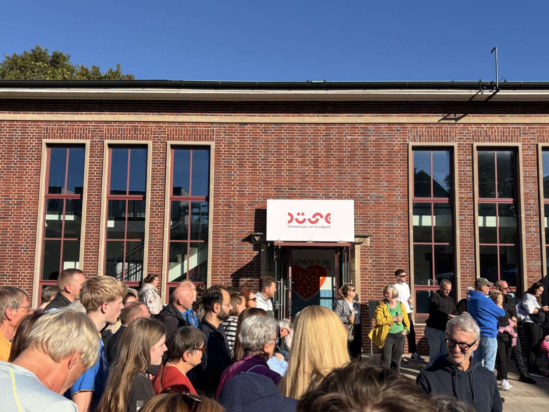 Das Düse-Backstein-Gebäude von außen. Es hat 6 schmale Fenster, die über beide Stockwerke gehen. Davor vielen Menschen, die alle nach rechts gucken. Dort scheint ein Vortrag oder ähnliches zu sein. Foto: Chris Meyer