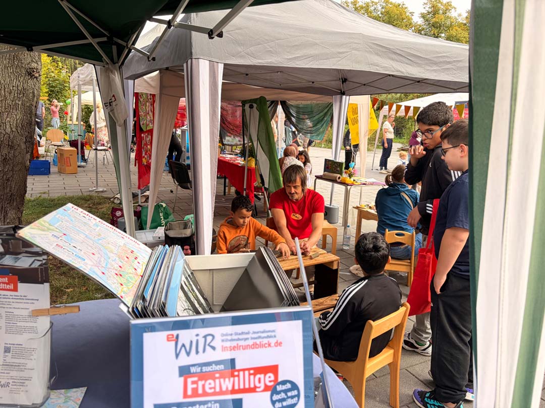 Unter einem Pavillon beschäftigen sich 2 Kinder und zwei Jugendliche unter Anleitung eines Erwachsenen mit Holzarbeiten Foto: Chris Meyer