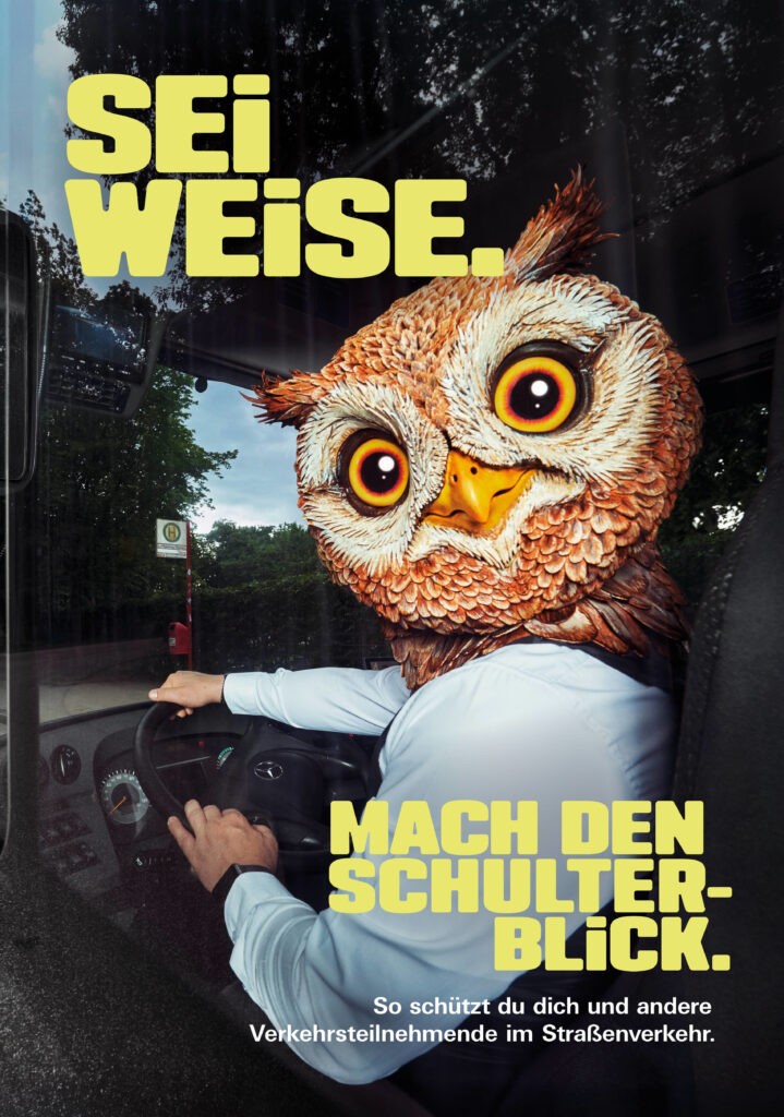 Kampagnenplakat. Am Steuer eines KFZ sitzt eine Figur mit Menschenkörper und Eulenkopf. Der Kopf ist weit über die Schulter zur Betrachterin gedreht. Sei weise, mach den Schulterblick. So schützt du dich und andere Verkehrsteilnehmende im Straßenverkehr.