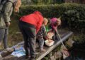 Auf einem Steg stehen zwei Frauen und drei Kinder mit einem Kescher