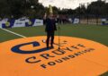 Schulleiter Clasing bei seiner Rede zur Eröffnung des Cruyff Court. Ersteht auf einem riesigen orangen Logo, das im Boden eingelassen ist.