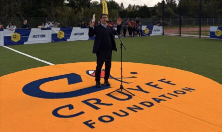 Schulleiter Clasing bei seiner Rede zur Eröffnung des Cruyff Court. Ersteht auf einem riesigen orangen Logo, das im Boden eingelassen ist.