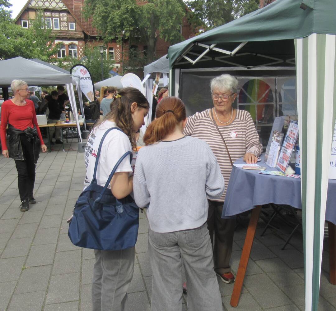 Der Stand des Wilhelmsburger Inselrundblicks auf dem Reiherstiegfest: Ein grüner Pavillon, darunter steht eine ältere Frau, die mit zwei jungen Frauen im Gespräch ist.