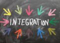 auf einem grauen Hintergrund steht in der Mitte das Wort Integration in weiß. Im Oval darum herum sind bunte Pfeile gemalt.